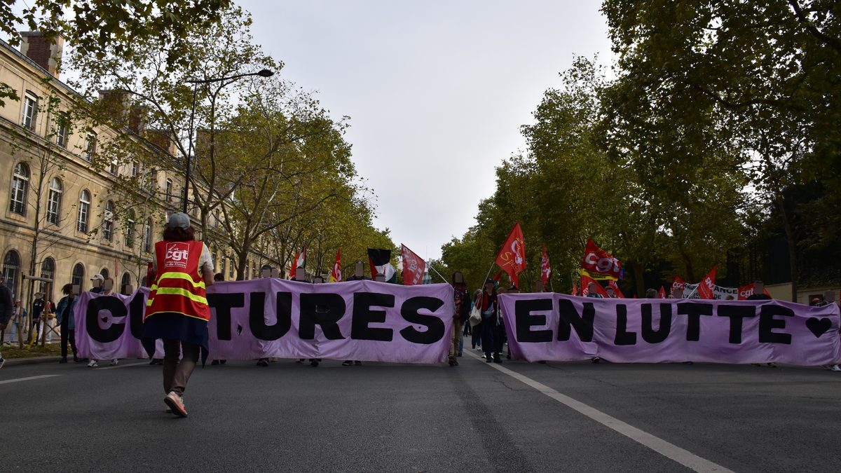 Tête de cortège derrière une banderole « Cultures en lutte » sur un boulevard parisien arboré, drapeaux de la CGT